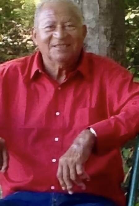 Smiling man in red shirt outdoors.