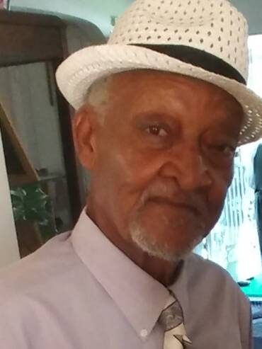 Elderly man wearing a white fedora hat.