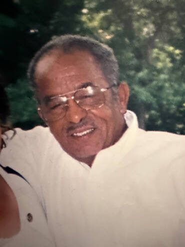 Smiling man in white shirt, outdoors.